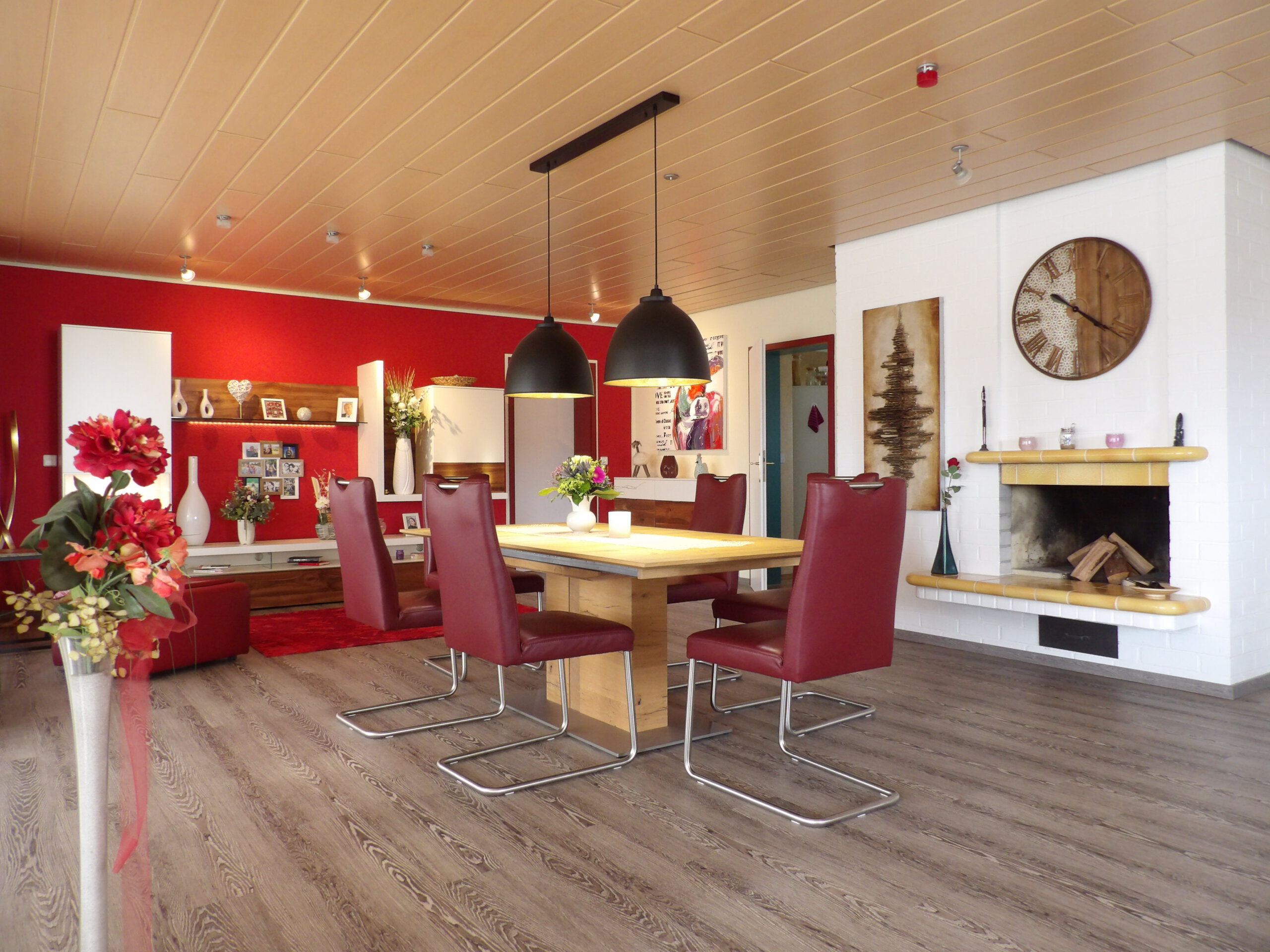 Esszimmer in einem Ettenheim Einfamilienhaus mit roten Stühlen, Holztisch, Pendelleuchten und gemütlichem Kamin—ein Wohntraum