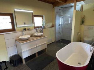 Modernes Schwanau-Badezimmer mit Doppelwaschbecken, ebenerdiger Dusche, freistehender Badewanne und viel Tageslicht in einer stilvollen Doppelhaushälfte