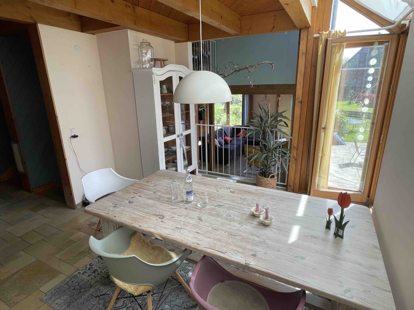 Heller Essbereich im Schwanau Architektenhaus mit Holztisch, verschiedenen Stühlen, Tulpen und Fenster zum Garten