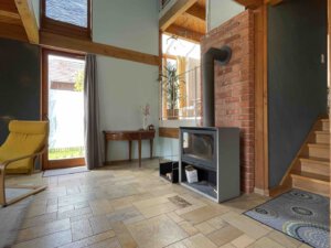 Moderner Architektenhaus-Wohnraum in Schwanau mit Holzofen, gemauertem Kamin, Fliesenboden und einfallendem Sonnenlicht