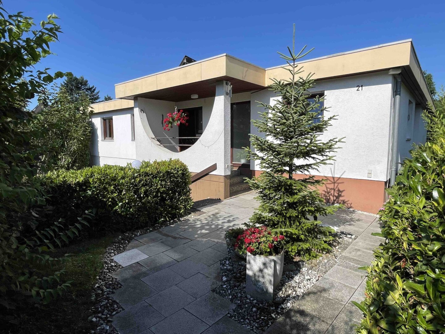 Moderner weißer Bungalow in Denzlingen mit Flachdach, Garage, Topfpflanzen, Steinweg und Gartentraum unter blauem Himmel